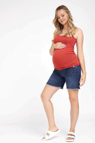 אישה לובשת ג'ינס להריון קרעים קצר כחול כהה של אבישג ארבל