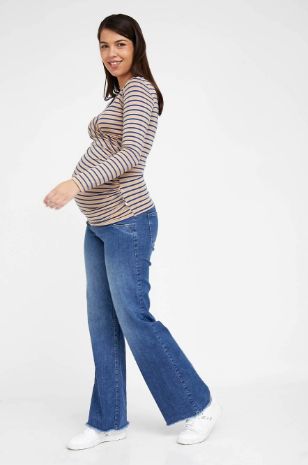אישה לובשת חולצת הריון מעטפת ש.ארוך קאמל פס ג'ינס