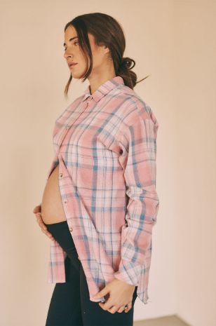 אישה לובשת חולצת הריון משבצות ורודה