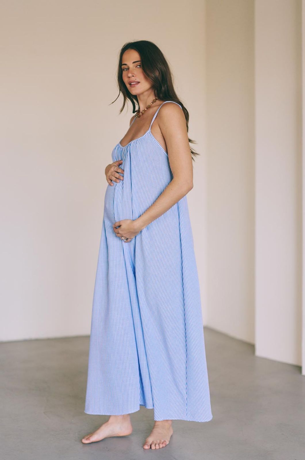 אישה לובשת שמלת הריון קיצית פסים תכלת לבן 