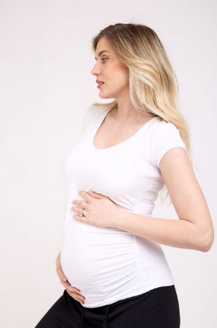 אישה לובשת חולצת הריון עם כיווצים לבנה