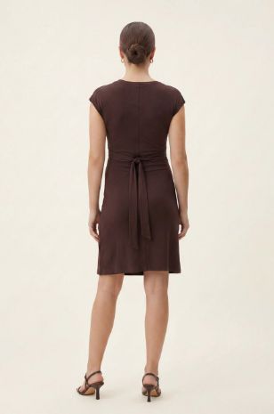 אישה לובשת שמלת הריון מיני עם סרט קשירה