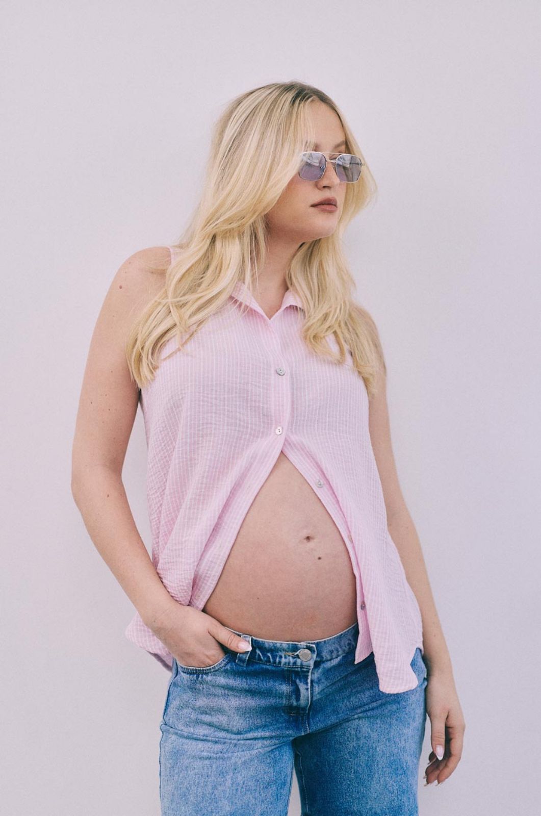 אישה לובשת חולצת הריון גברית ללא שרוול פס שמנת ורוד של אבישג ארבל